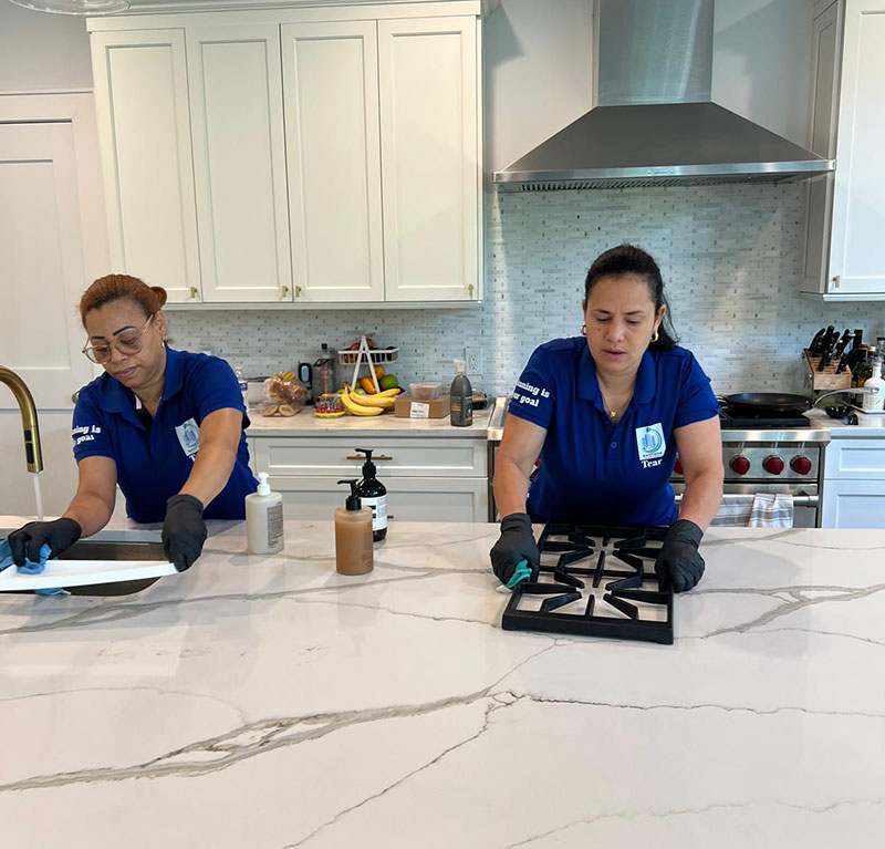 Professional cleaners deep cleaning stove grates and kitchen surfaces