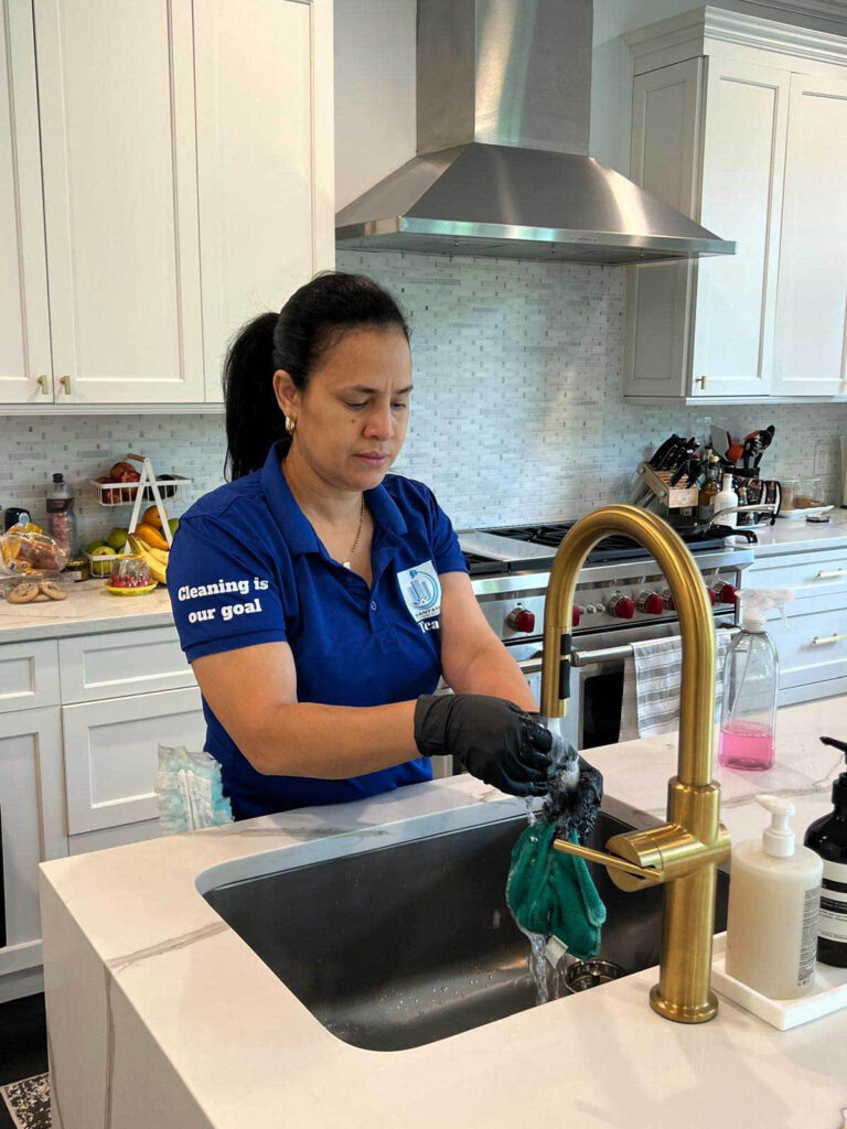 Professional cleaner from Santana Cleaning Services washing cleaning cloths in a modern New Jersey kitchen sink