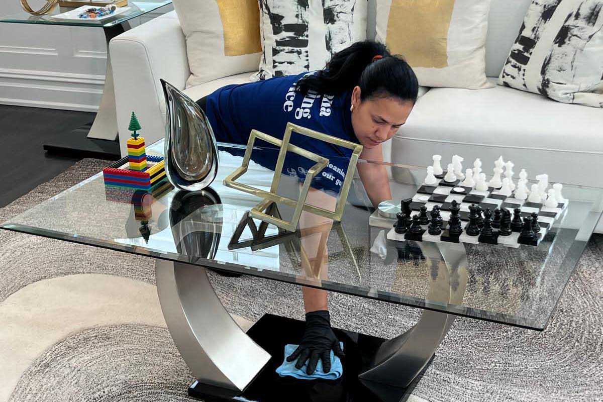 Santana Cleaning Services specialist polishing a luxury glass coffee table in a New Jersey living room.