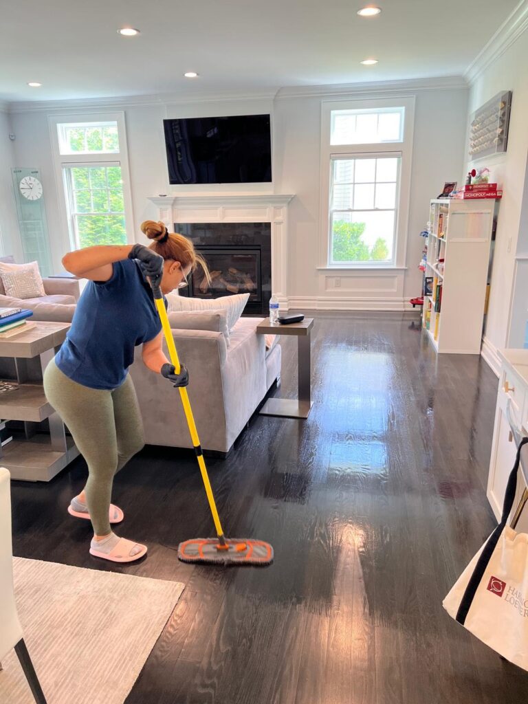 "Professional cleaner from Santana Cleaning Services mopping and deep cleaning hardwood floors in a New Jersey home living room"
