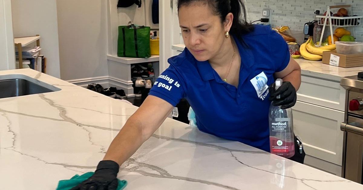Professional cleaning service employee sanitizing a kitchen surface